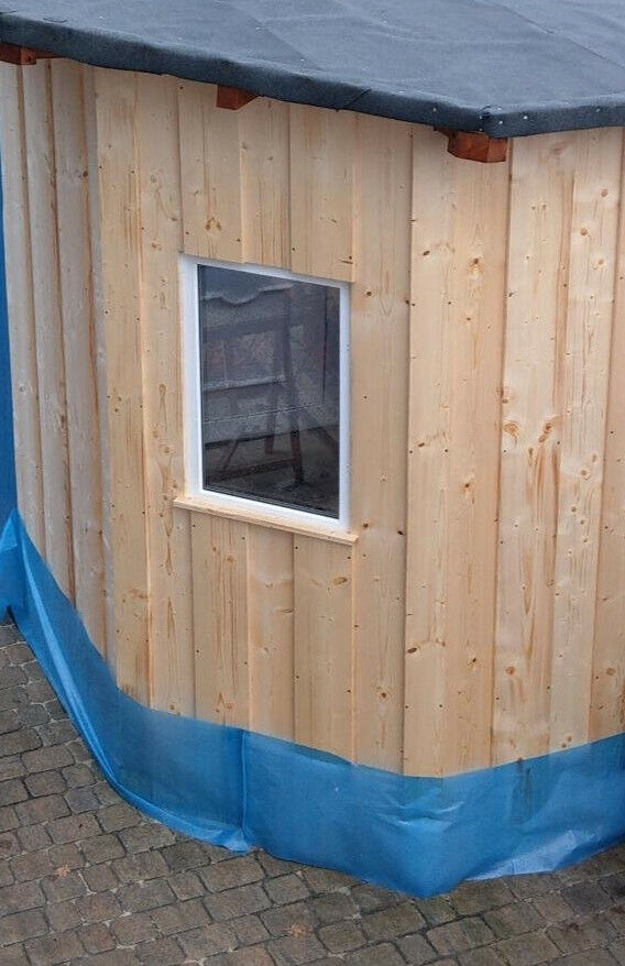 Eine Holzhütte mit einem Festverglasten Kellerfenster.